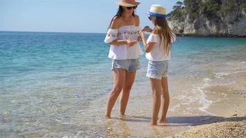 Beautiful mother and daughter at Caribbean beach enjoying summer vacation. video