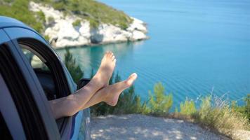 vicino su di poco ragazza piedi mostrando a partire dal auto finestra sfondo mare video