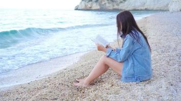 mujer joven leyendo en la playa blanca tropical video