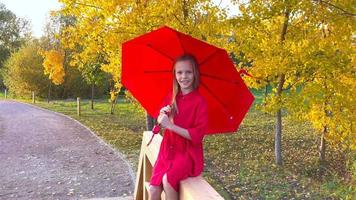 glückliches Kindermädchen lacht unter rotem Regenschirm video