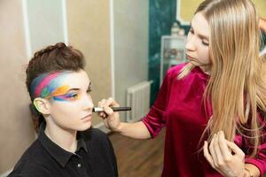 Artist applies makeup to a young model photo