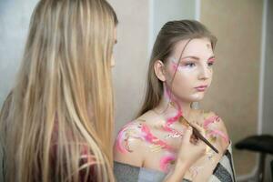 The artist applies makeup to a cute young model photo