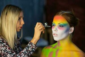 The artist puts a face painting on a lovely young model photo