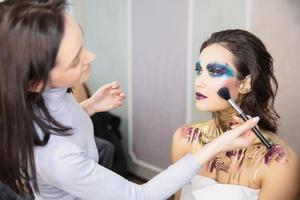 The artist applies makeup to a alluring young model photo