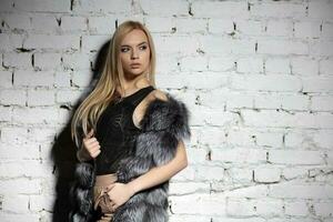 Lovely blonde posing near a brick wall photo