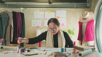 créatrice de mode asiatique d'âge moyen travaillant dans un studio par idée dessinant des croquis avec du fil coloré et cousant pour une collection de conception de robe, boutique professionnelle tailleur PME entrepreneur. video