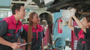 A male professional automotive supervisor and Black female inspector check repair work with female mechanic worker at car garage, service maintenance, and fix specialist occupations in auto industry. video