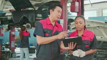 Male professional automotive supervisor and Black female coworker discuss and inspect repair work checklists at car garage, service maintenance, and fixing specialist occupations auto industry.