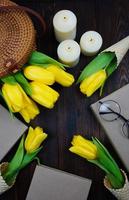 A flatley of yellow tulips is laid out on a wooden table photo