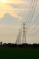 High-voltage poles are used to carry electricity for industrial plants and people to use in the farmer's fields in the evening. Beautiful sky atmosphere and designed by electrical engineers. photo