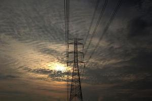 High-voltage poles are used to carry electricity for industrial plants and people to use in the farmer's fields in the evening. Beautiful sky atmosphere and designed by electrical engineers. photo