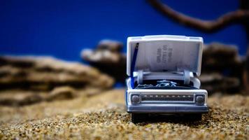 minahasa, Indonesia January 2023, a toy car on the sand with a background of rocks and blue sky photo