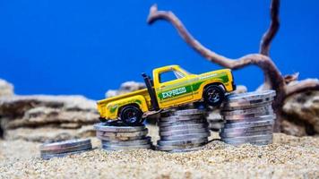 minahasa, Indonesia  January 2023, toy car on a pile of coins, saving for the future, managing successful transportation business technology concept photo