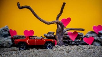 Minahasa, Indonesia  December 2022, toy car with gradient orange background and a heart photo