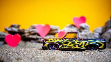 Minahasa, Indonesia  December 2022, toy car with gradient orange background and a heart photo