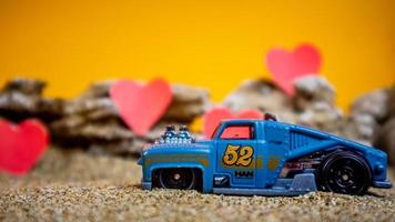 Minahasa, Indonesia December 2022, toy car with gradient orange background and a heart photo