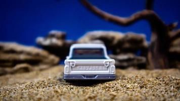 minahasa, Indonesia  January 2023, a toy car on the sand with a background of rocks and blue sky photo