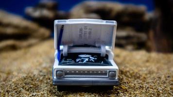 minahasa, Indonesia  January 2023, a toy car on the sand with a background of rocks and blue sky photo