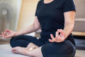 Asian elderly woman meditating practicing yoga for good health At an older age, it's about taking care of your body's health at home on a relaxing day. good health concept photo