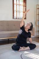 Asian elderly woman meditating practicing yoga for good health At an older age, it's about taking care of your body's health at home on a relaxing day. good health concept photo