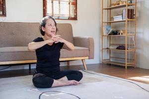 Asian elderly woman meditating practicing yoga for good health At an older age, it's about taking care of your body's health at home on a relaxing day. good health concept photo