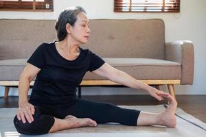 Asian elderly woman meditating practicing yoga for good health At an older age, it's about taking care of your body's health at home on a relaxing day. good health concept photo