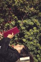 hermosa mujer leyendo en el jardín acostado en de madera mesa foto