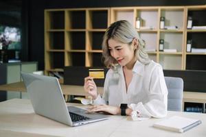 Woman using smart phone for mobile payments online shopping,omni channel,sitting on table,virtual icons graphics interface screen in morning light photo