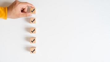 Checklist concept, wooden cubes with check marks on white table. Checklist, form filled in business. photo