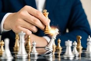 leadership concept, businessman hand catches golden chess king checkmate in chessboard tournament, business team challenge, winner in global industry. photo