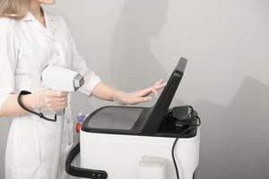 woman wearing white medical uniform holding laser epilation machine device. beauty and skincare with diode laser. photo