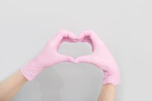 del doctor manos en rosado médico guantes en forma de corazón en gris fondo, Copiar espacio. salud, farmacia y medicamento, cuidado para el corazón salud foto