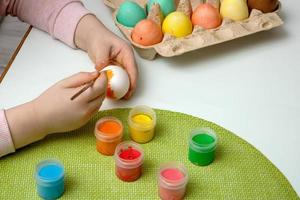 para niños manos pintar Pascua de Resurrección huevos, en el mesa allí son pinturas y un cesta con vistoso huevos foto