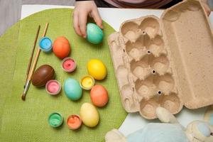 child's hand is going to put colored Easter eggs into an empty basket photo