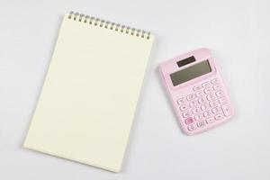 plano laico de rosado calculadora con blanco página abrió cuaderno. negocio y educación concepto. foto