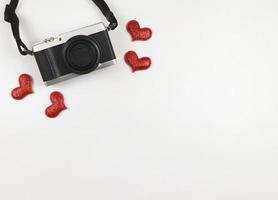 flat lay of digital camera with red glitter hearts on white background with copy space. photo