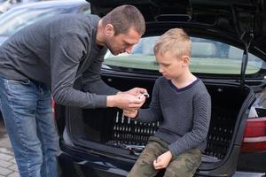 Dad teaches his cute son to use a car repair tool photo