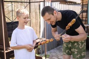 Funny dad and son try grilled meat photo