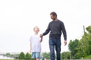 A father walks with his son on the road. The child is indulging photo