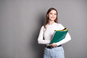 un linda estudiante niña sostiene cuadernos para notas y sonrisas foto