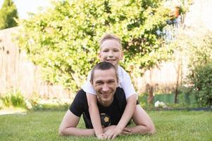 A cute baby is lying on his father's back. Lying on the lawn photo