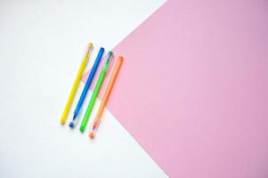 A set of stationery on a white and pink background, pens of different colors photo