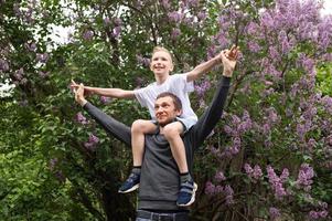 Dad picked up and put a cute child on his shoulders. Son flies like a plane photo