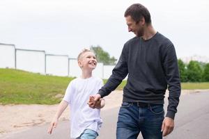 A father walks with his son on the road. The child is indulging photo