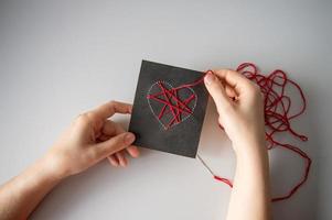 Making a postcard with a heart using thread printing on black cardboard photo