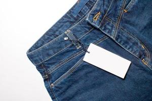 Mock-up of a white price tag card for clothes on blue denim trousers photo