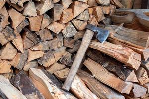 The stacked lumber lies in the woodpile. Axe with wooden handle photo