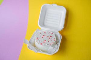 An open box with a Valentine's Day bento cake with hearts stands on a yellow background photo