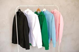 Hoodies of different colors hang on a hanger photo