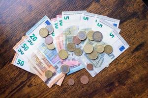 Euro banknotes and coins are lying on a wooden table photo